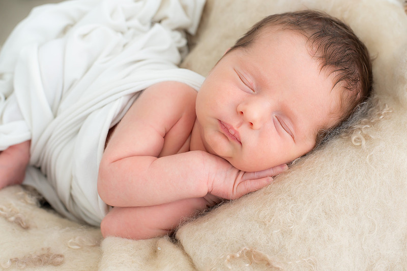 Sleeping newborn on cream wool